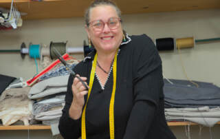 La modista artesana Elisa Durán sonríe, tijeras en mano y cinta métrica colgada del cuello